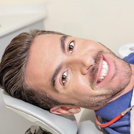 Man lying back in dental chair and smiling